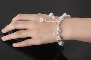 Person with silver charm bracelet Australia Silver color, front view, showing hollow beads.