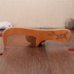 Person with wooden comb Australia Peach wood color, front view, showing comb teeth.