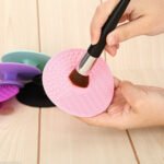 Person with silicone makeup brush cleaner Australia Multi-coloured, front view, showing ridged design.