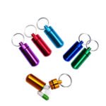 Person with portable pill box Australia Silver color, front view, showing keychain design.