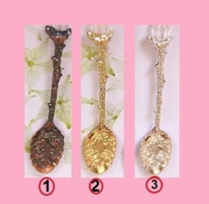 Person with retro fruit spoon Australia Silver/Gold/Copper color, front view, showing elegant design.