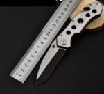 Person with camping knife Australia Steel color, front view, showing folded blade.