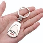 Rugged metal car keychain with Audi emblem against a rugged backdrop