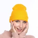 Person in acrylic winter beanie hat Grey color, front view, showing knitted design.