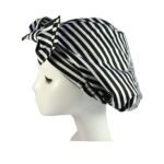 Woman using reusable turban shower cap Tropical Leaf color, front view, showing bow design.