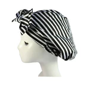 Woman using reusable turban shower cap Tropical Leaf color, front view, showing bow design.