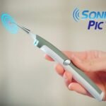 Person with electric tooth stain eraser Australia White/Grey color, front view, showing LED light.