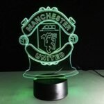 Red Manchester United 3D LED lamp glowing on a bedside table.