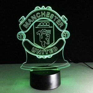 Red Manchester United 3D LED lamp glowing on a bedside table.