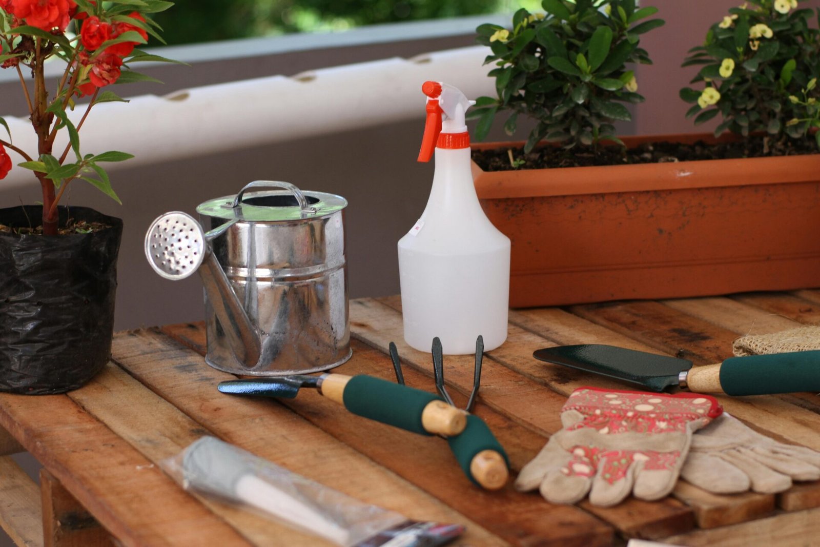 Collection of essential garden tools including soil tester, watering timer, tap lock, and decorative garden stakes arranged on a wooden surface